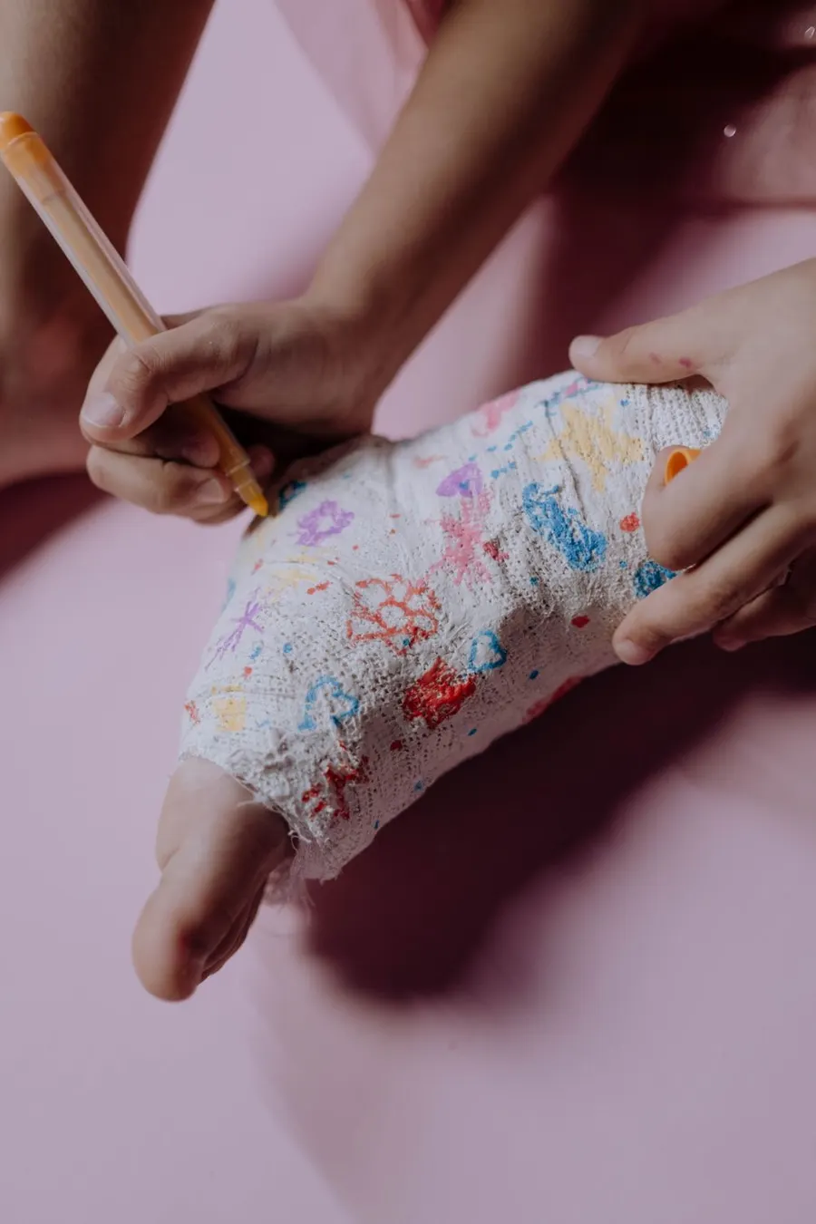Child drawing with colour pens on an arm cast