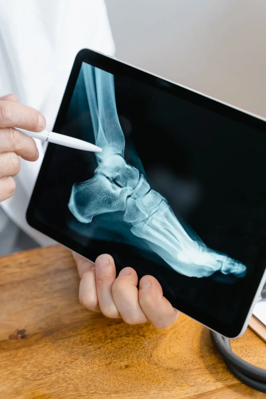 Orthopaedic doctor reviewing a bone X-ray on a tablet — accurate diagnosis before treatment